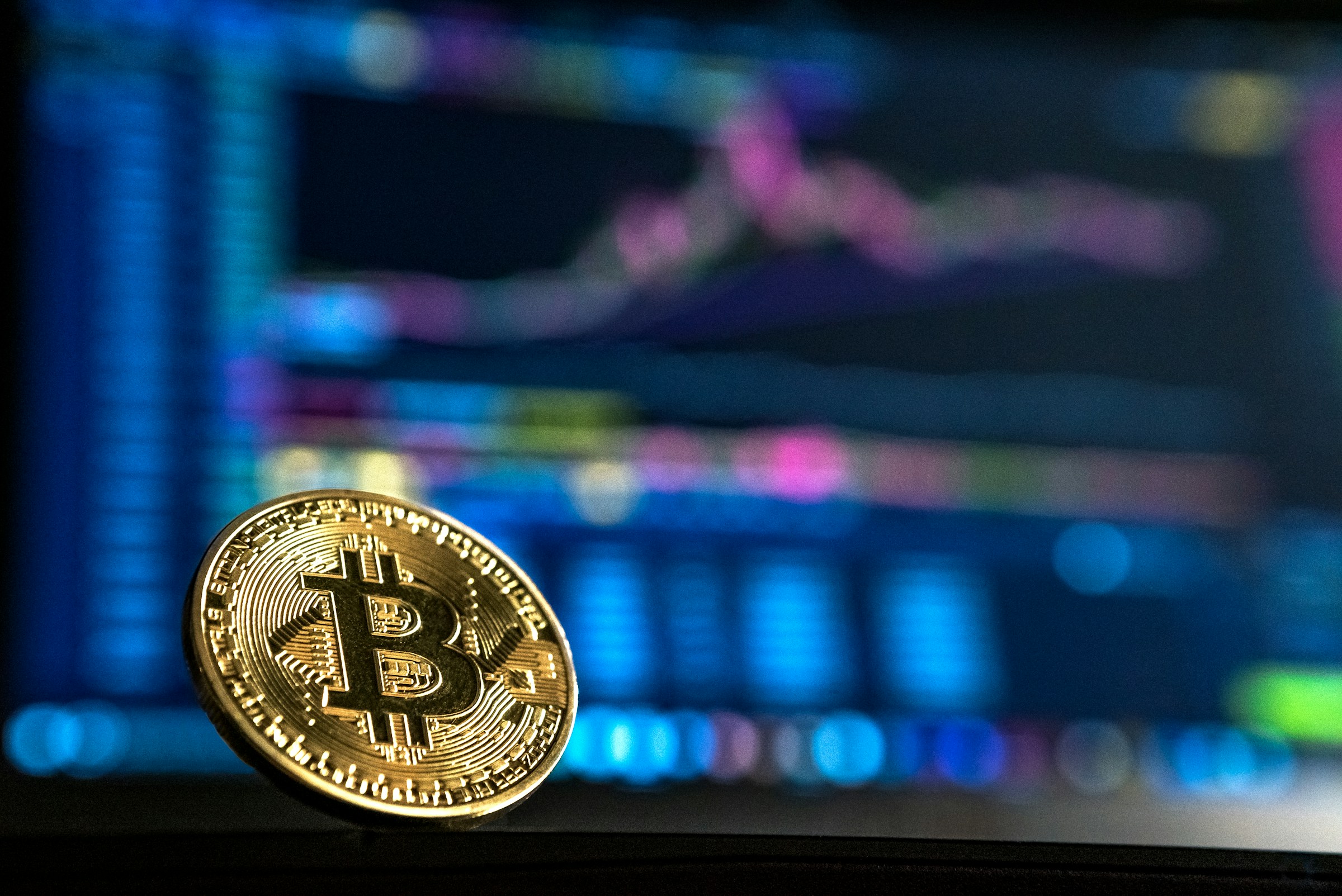 Eine physische Bitcoin-MĂŒnze vor einem Marktdiagramm